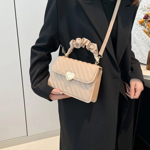 Minimalist beige crossbody bag with quilted pattern, heart lock, and ruched handle