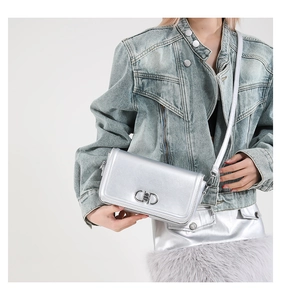 Silver crossbody bag with metal CD buckle on model wearing denim jacket and skirt