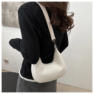 Detailed view of white crocodile pattern hobo bag with gold hardware worn by a model