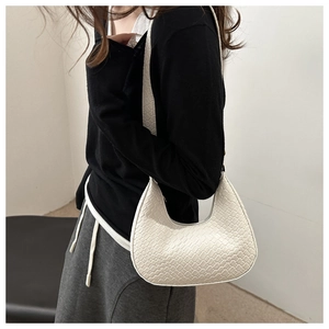 Close-up of beige crescent hobo bag showing woven texture and sleek shoulder strap