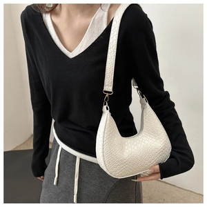 On-body view of a white crescent shoulder bag with embossed crocodile texture and wide strap