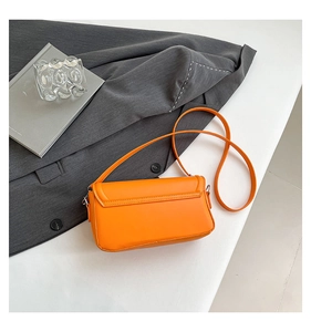 Detailed top view of bright orange rectangular flap shoulder bag on neutral background