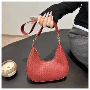 Macro detail of red woven texture on crescent shoulder bag with golden metal hook