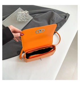 Detailed interior of orange leather crossbody bag showing zipper pocket and metal lock