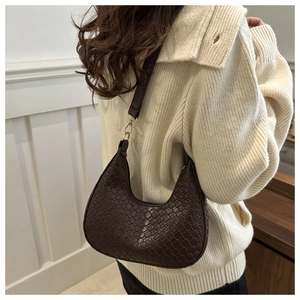 Detail of dark brown crescent underarm bag showing woven leather texture and gold metal buckle