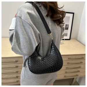 Detail of black crescent moon shoulder bag with crocodile texture on female model