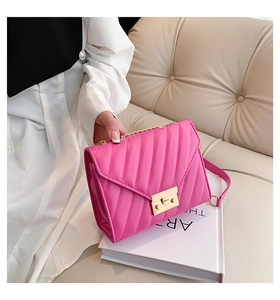 Detail of rose pink quilted crossbody bag with gold metallic lock and chain strap