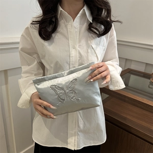 Silver grey satin clutch bag featuring delicate butterfly embroidery and silk texture