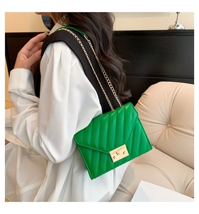 Close-up of emerald green quilted crossbody bag with gold chain strap and metal clasp