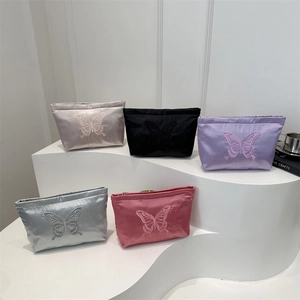 Satin makeup pouches with butterfly embroidery in five colors on white display stands