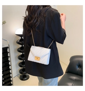 Close-up of white quilted crossbody bag featuring a gold metal lock and chain strap