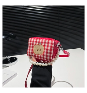 Macro detail of red plaid makeup bag with apple patch and pearl handle accents