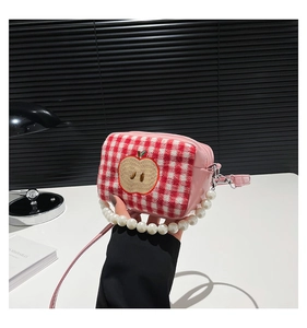 Close-up of pink plaid makeup bag featuring apple embroidery and pearl handle detail