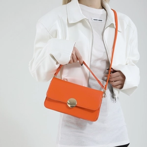 Sac bandoulière orange minimaliste avec boucle dorée ronde et longue bandoulière