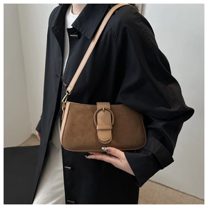Detailed view of brown matte suede shoulder bag with circular textured metal buckle