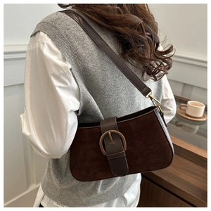 Detail of dark brown matte suede shoulder bag featuring a vintage gold round buckle