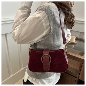 Detail of burgundy matte suede moon bag featuring a large gold horseshoe metal buckle