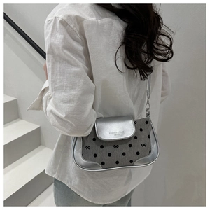Detail of grey polka dot shoulder bag with silver metallic flap worn by a model