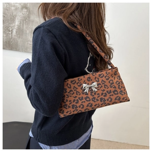 Detail of leopard print underarm bag featuring a metallic silver butterfly clasp accent