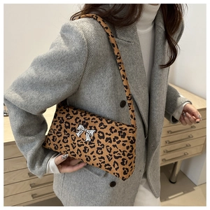 Detail of leopard print shoulder bag with silver butterfly buckle on a wool coat