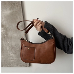 Close-up of vintage brown PU leather shoulder bag with gold metal buckle and zipper