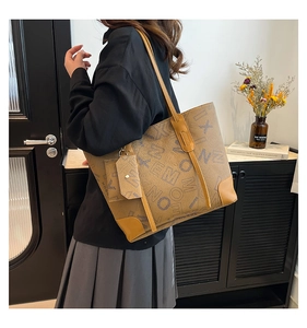 Close-up of brown letter print tote bag with reinforced leather corners and matching pouch