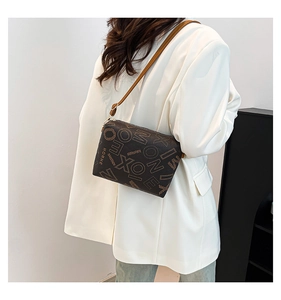 Détail du sac cabas vintage en cuir marron avec logo porté par un mannequin en blazer