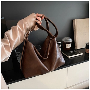 Detail of dark brown tote bag showing smooth leather texture and wide shoulder strap