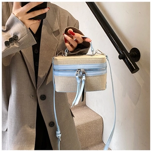 Detail of beige woven mini box bag with sky blue leather trim and dual zippers