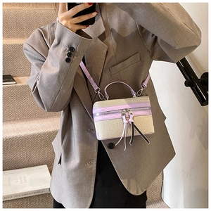 Close-up of a canvas box bag with purple leather trim and long decorative tassels