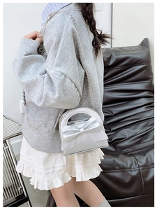Silver bow shoulder bag for kids with metallic chain strap worn by child model