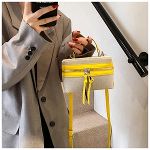 Crossbody box bag with yellow leather trim, woven texture, and long tassel zipper detail
