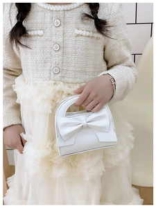 Detail of white mini bow handbag with textured leather for elegant girls' party outfit