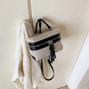 Detailansicht der beigen Web-Box-Tasche mit schwarzen Lederbesätzen und Quasten