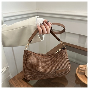 Detail of brown tweed woven texture with gold FASHION & BAGS metal logo on shoulder bag