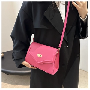 Macro detail of hot pink square bag featuring a gold oval twist lock and smooth PU leather