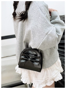 Detail of girls black bow handbag showing silver chain strap and stylish side view