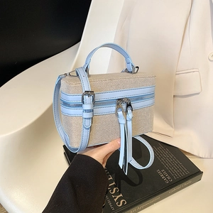 Details der Box-Handtasche mit beigem Webmuster, hellblauen Lederkanten und Quasten