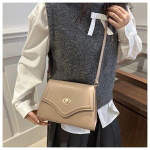Detail of minimalist beige envelope bag featuring a gold round twist lock and smooth texture