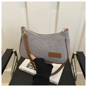 Detail of gray denim shoulder bag with brown leather trim and metallic gold hardware
