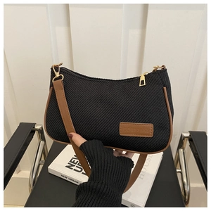 Detail of black knit tote bag with brown leather trim and gold hardware