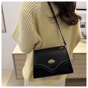 Detail of black vintage crossbody bag with gold oval twist lock on a yellow knit sweater