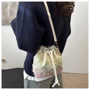 Detail of drawstring bucket bag featuring colorful star prints and frayed edge texture