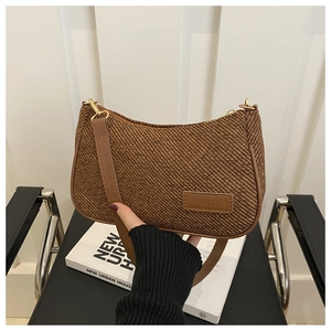 Detail of brown woven hobo bag showing fine texture and leather logo tag held by a model