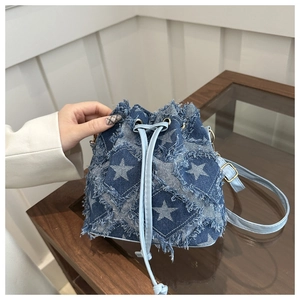 Close-up of blue denim bucket bag featuring white star patterns and frayed edge texture