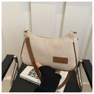 Detailed view of beige woven texture with a brown leather strap and embossed fashion tag