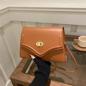 Close-up of caramel retro faux leather handbag with a golden V-shape metal twist lock