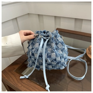 Detail of blue denim checkered bucket bag showing frayed edges and drawstring closure