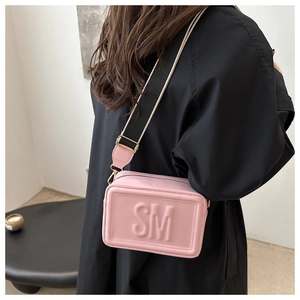 Detail of pink crossbody bag with SM embossed logo and wide woven shoulder strap