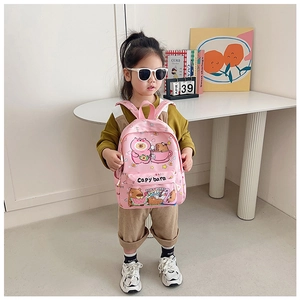Pink cartoon capybara backpack shown on model in a cozy indoor student room setting